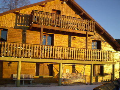      Façade ouest de la ferme dont la façade avec bardage bois et balcons lui donne l'apparence d'un chalet.